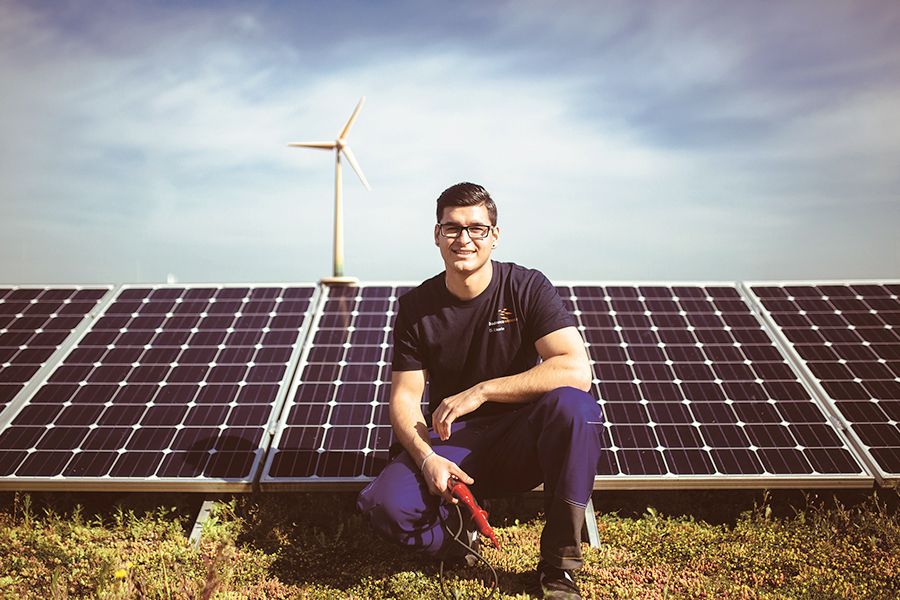 Ein Kollege der badenovaWÄRMEPLUS auf dem Dach des Hauptgebäudes am Standort Freiburg. Im Hintergrund: Photovoltaikanlage und Windräder.