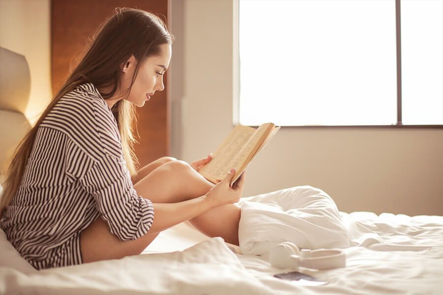 Frau liest im Bett ein Buch.