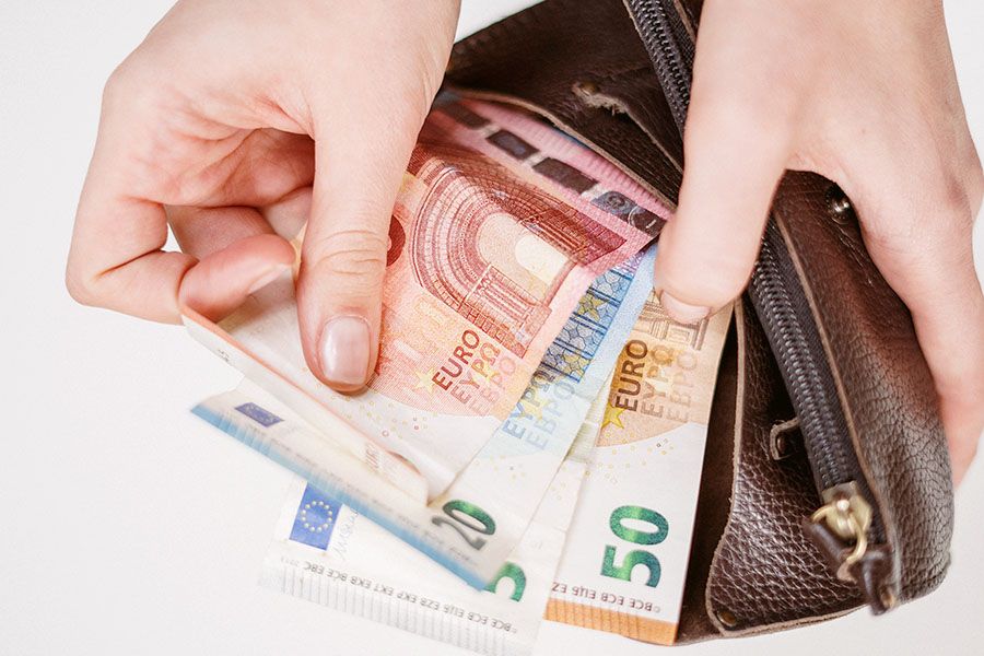 Hände halten Portemonnaie und Geldscheine in der Hand.