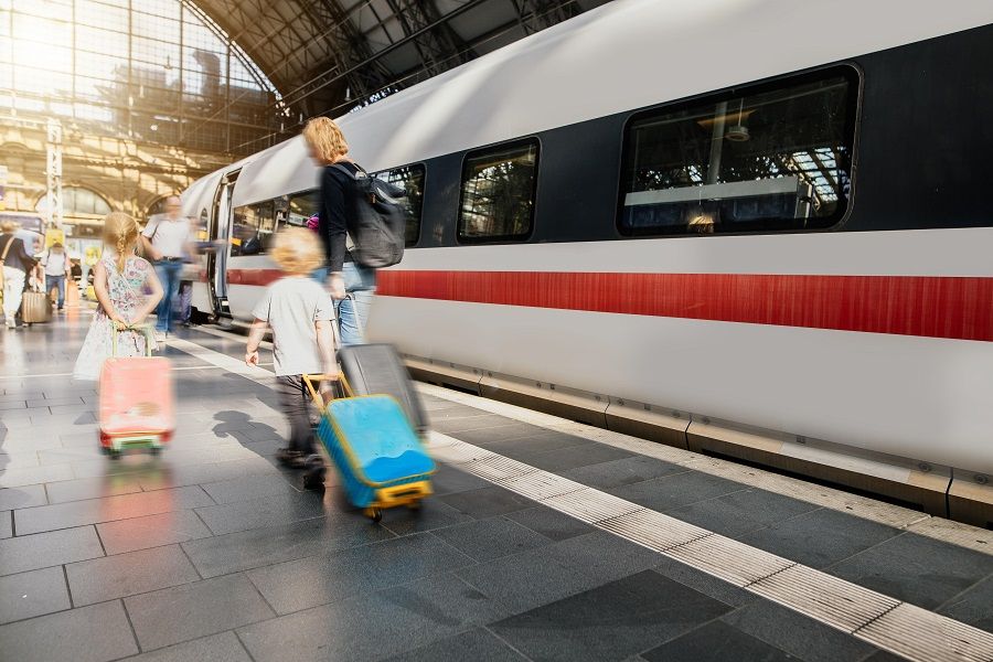 Familie mit Koffern am Bahnhof eilt zum Zug.