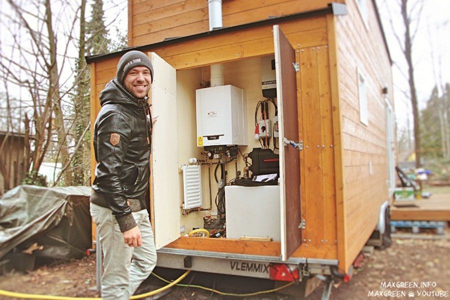 Max steht vorm Technikraum seines Tiny Houses.